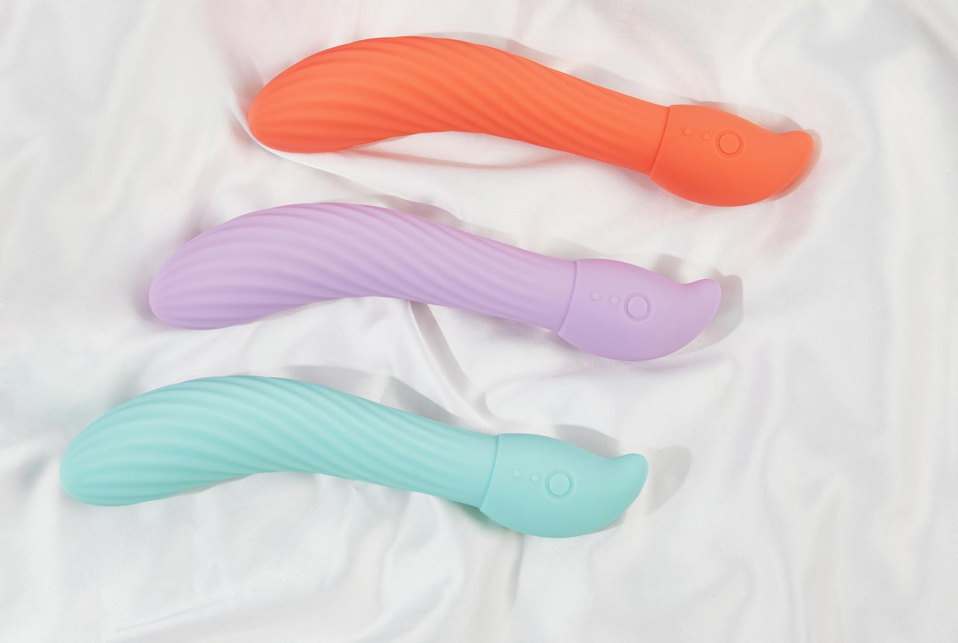 Three colorful lemon vibrators arranged on white fabric showing their smooth curved shape