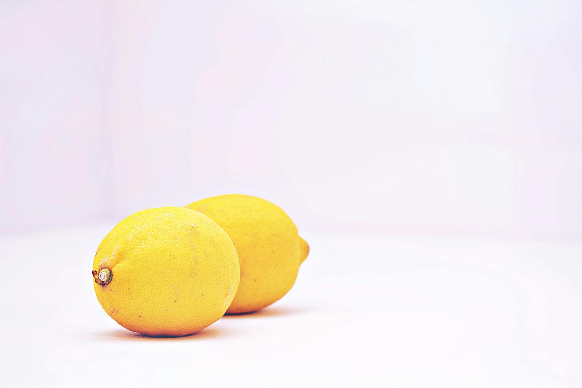 Two women laughing together with lemon slices, expressing intimacy and joy