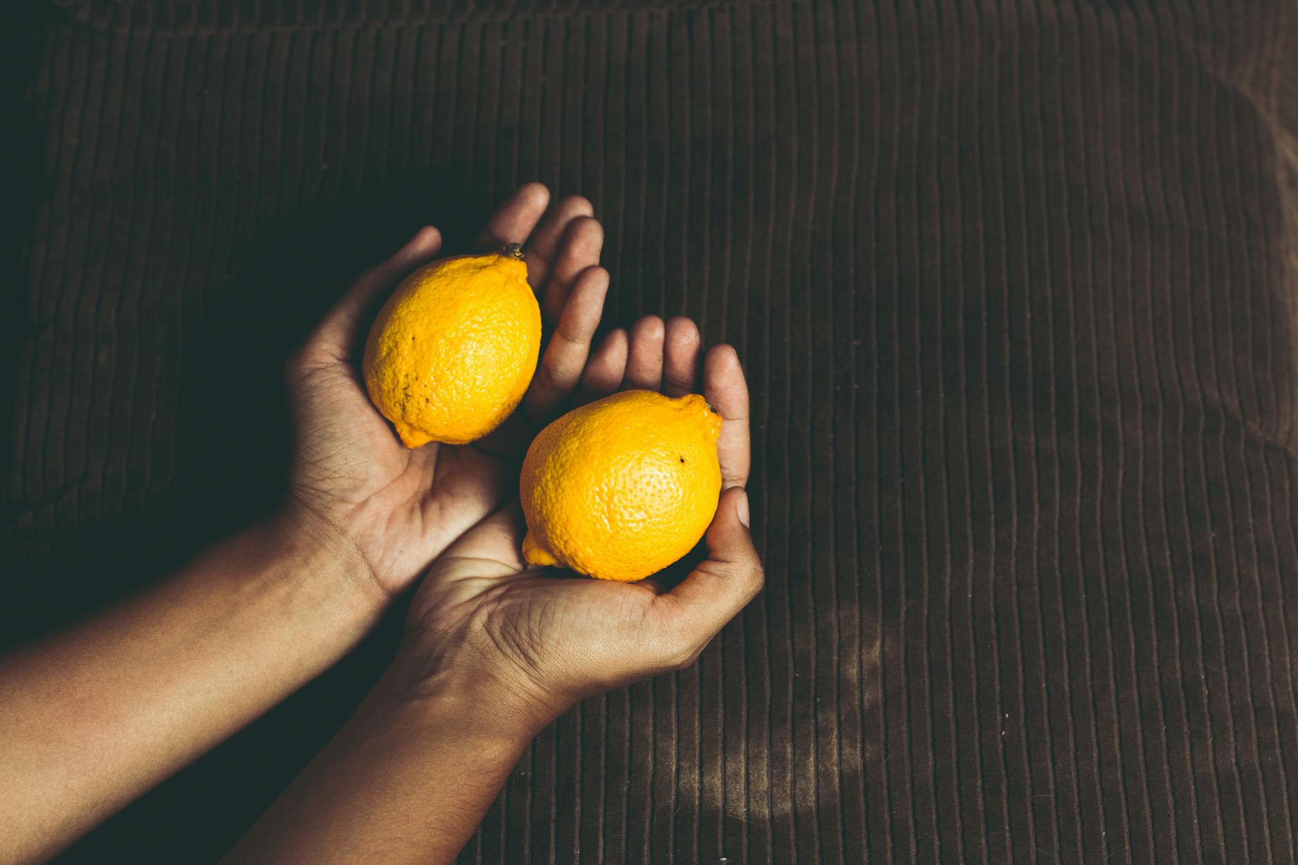 Two hands holding fresh lemons together, symbolizing partnership and shared pleasure
