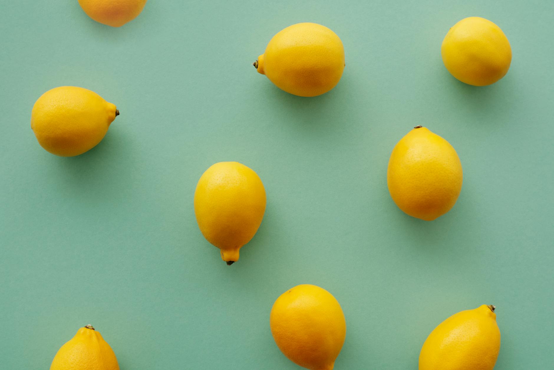 Bright yellow lemons on a pastel green background, symbolizing fresh pleasure and sensuality
