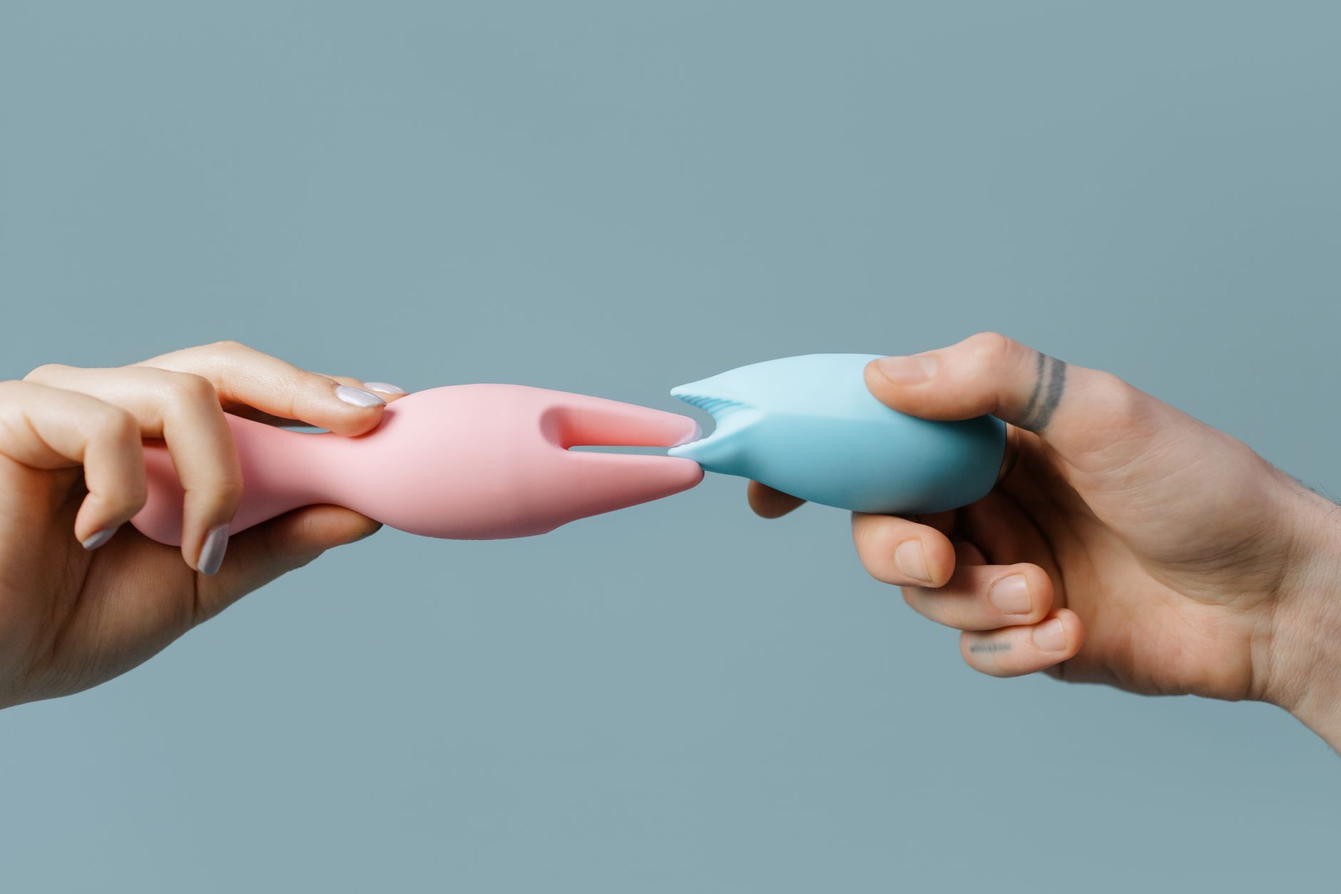 Hands holding pastel-colored silicone adult toys, symbolizing pleasure recovery and gentle sensation