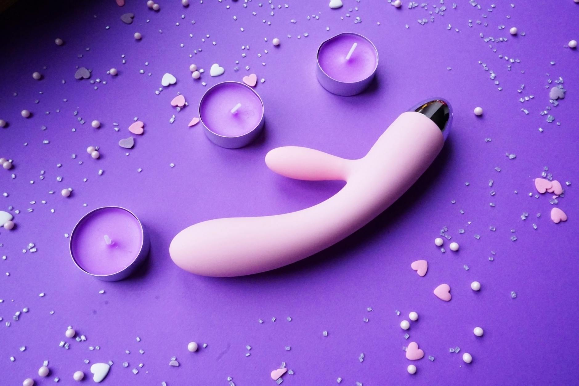 A vibrator on a soft surface with candles, representing intimacy during pregnancy