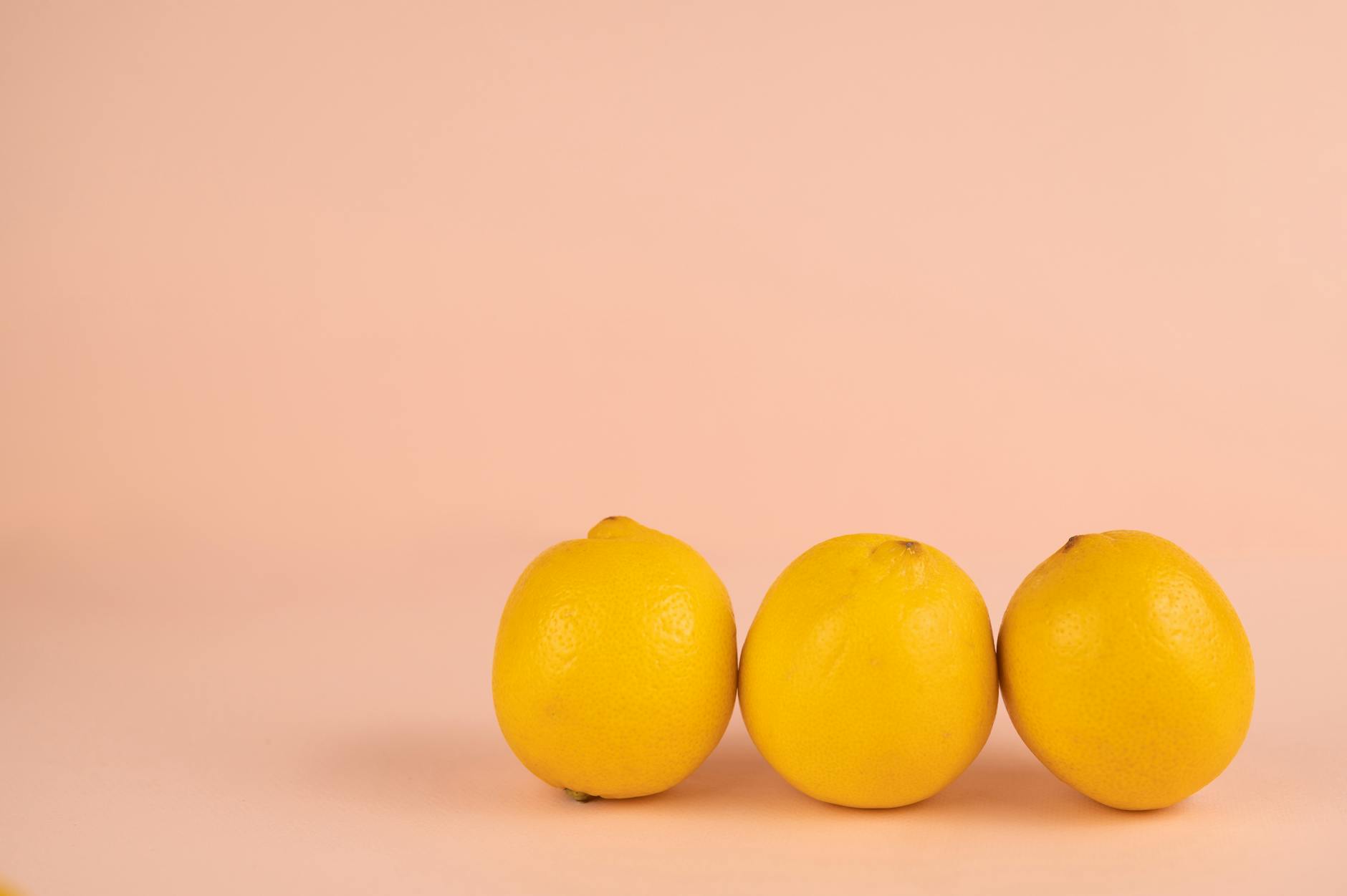 Bright ripe lemons with pleasant aroma and pedicels on peel on pastel background
